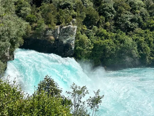 Imponente cascada turquesa que desciende por una frondosa garganta de bosque verde