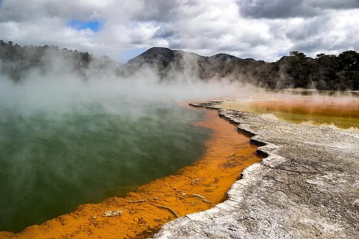 Stomende geothermische poel met levendig groen water en oranje rand