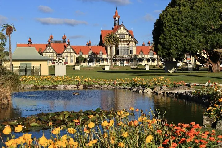 Historisch gebouw met een rood dak achter een vijver en oranje bloemen