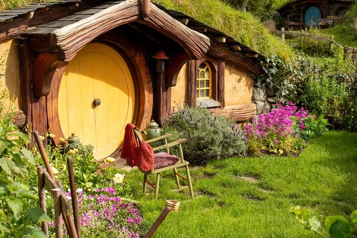 Close-up van een hobbitgat met een gele ronde deur.