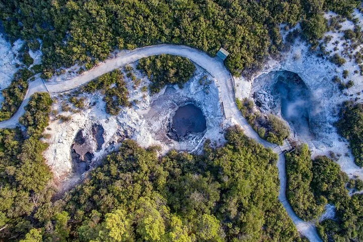 Luchtfoto van bovenaf van een kronkelend pad door een geothermisch gebied met poelen.